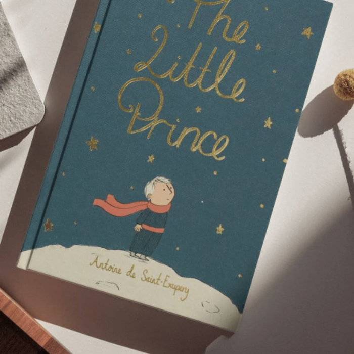 Book titled 'The Little Prince' with a child illustration on a blue background.