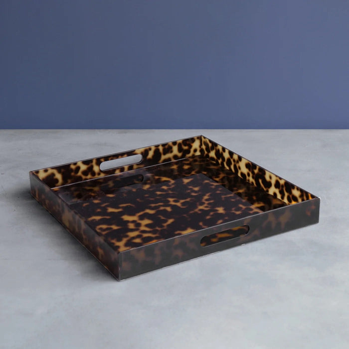 Beatriz Ball Vida Acrylic Tortoise Large Square Tray With Handles — Empty tray on a gray surface against a blue wall