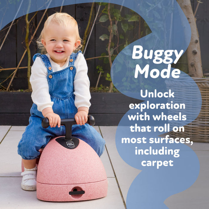 A smiling toddler in blue overalls sits on a pink Boogie Buggy with handlebars. Text reads: Buggy Mode. Unlock exploration—its wheels roll smoothly on most surfaces, even carpet.