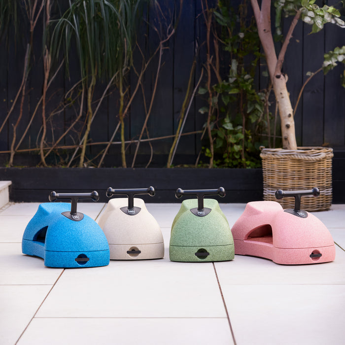The Boogie Buggy | Sage, a colorful ride-on toy for children, is shown on a tiled patio with plants and a woven basket in the background.