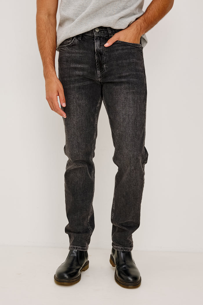 Clayton Slim Straight Jean With 5-Pocket Styling, Belt Loops, and Front Zip-Fly in Faded Onyx Colorway - Lower Body Front View Featured on Model