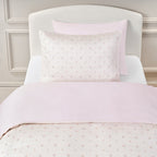 Twin bedding set in the pattern Ditsy Floral in Pink on a bed with a white headboard.