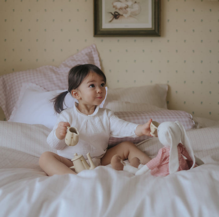 Child playing with toys on a bed in a cozy bedroom setting.