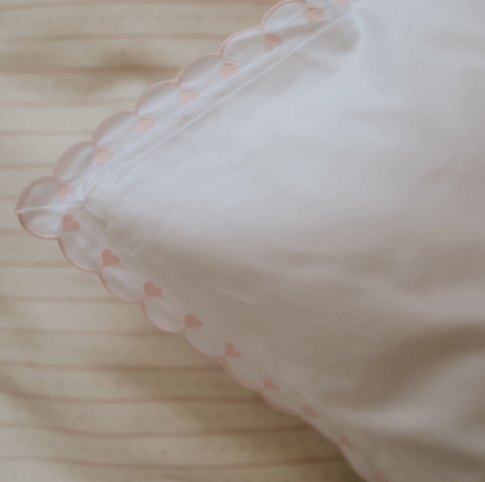 White pillow with pink heart pattern on a soft surface