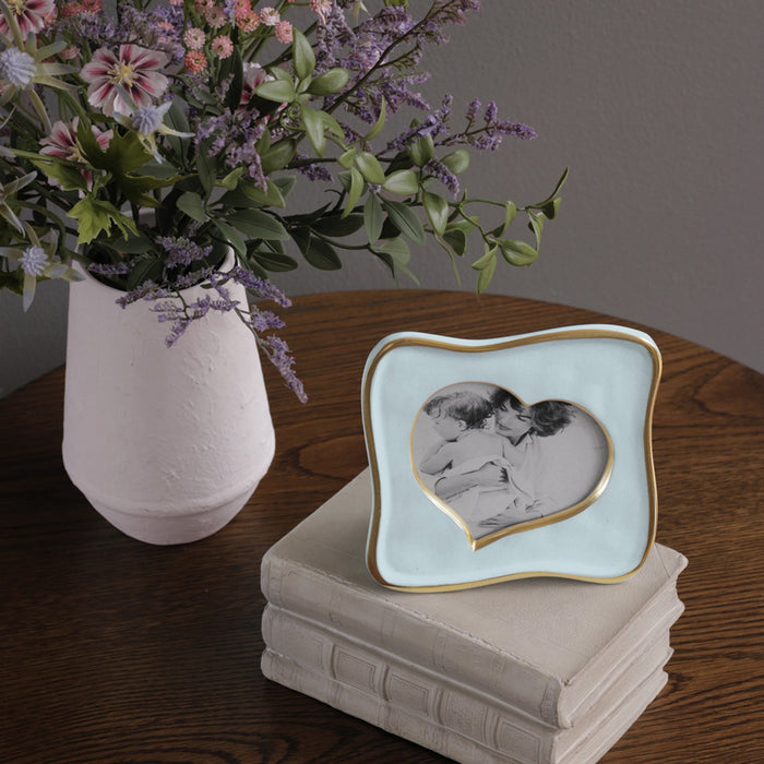 Beatriz Ball Frame Encanto Curved Heart 5 x 5 — Standing on books beside flowers