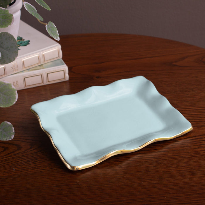 Beatriz Ball Encanto Vento Small Rectangular Tray — Angled view on a wooden surface beside books