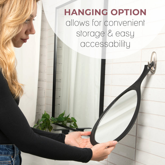 Zadro ZHSL1BLK 705004424837 environment photo side view user hanging by ergonomic handle hook on bathroom wall with features, new large teardrop handheld mirror with hanging handle in front of a real life setting