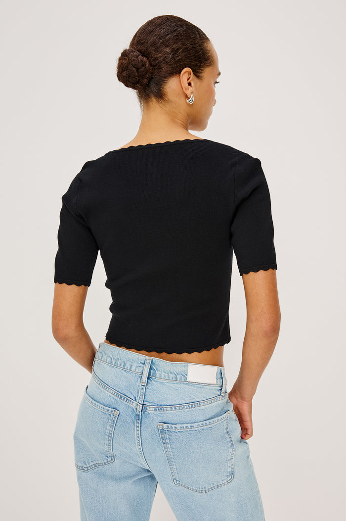 Louanna Fitted Cropped Top in Compact Knit With Scallop-Trimmed Scoop Neckline, Short Sleeves, and Hem in Black Colorway - Upper Body Back View Featured on Model
