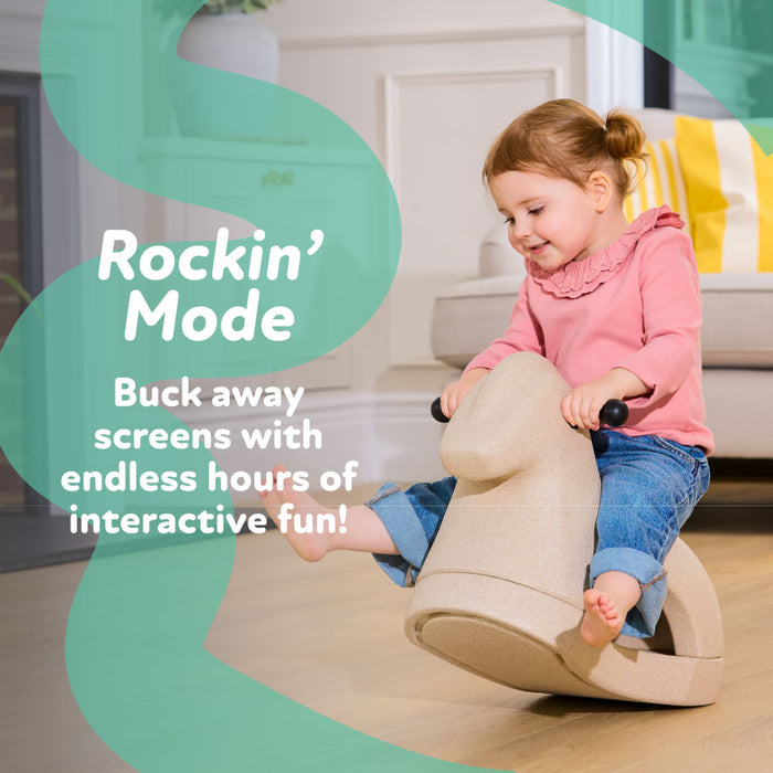 A young child in a pink top and jeans smiles while rocking on the beige Rock 'N Ride | Pink indoors. The text reads: “Rockin’ Mode. Buck away screens with endless hours of interactive fun!”.