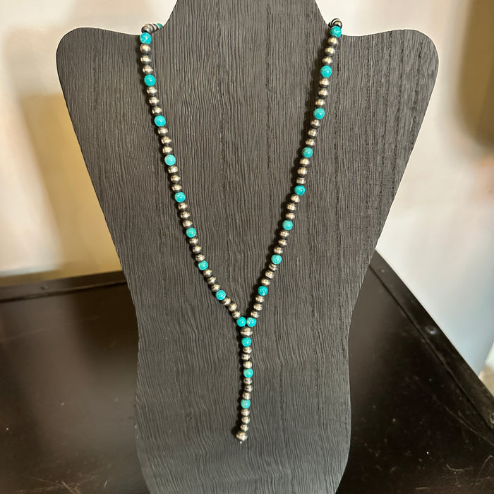 Turquoise and silver bead necklace on a black display stand.
