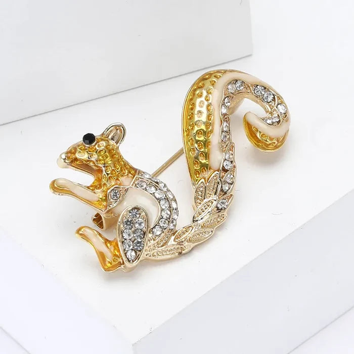 Gold squirrel brooch with rhinestone details on a white background