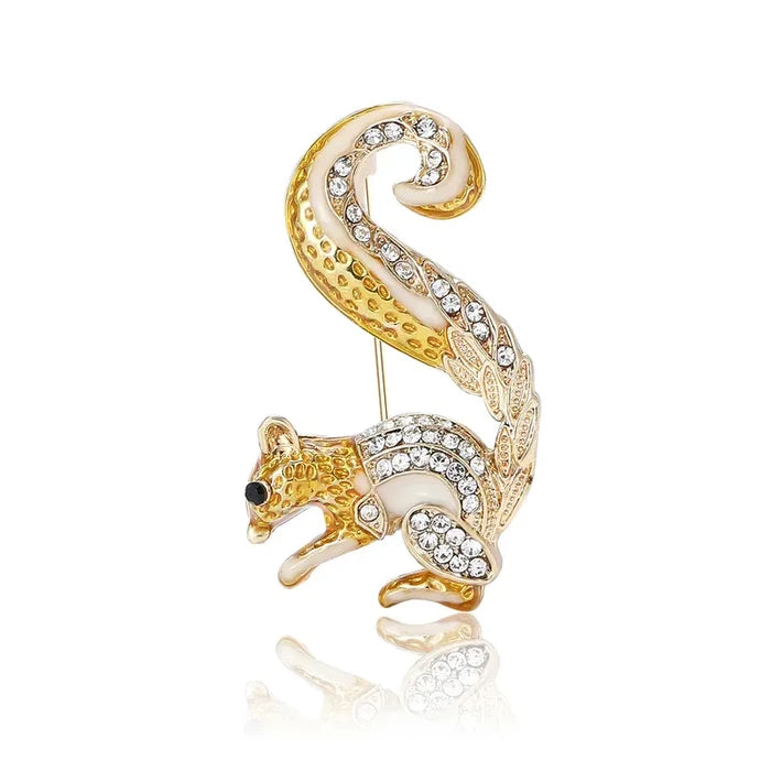 Gold and white squirrel-shaped brooch with rhinestones on a white background