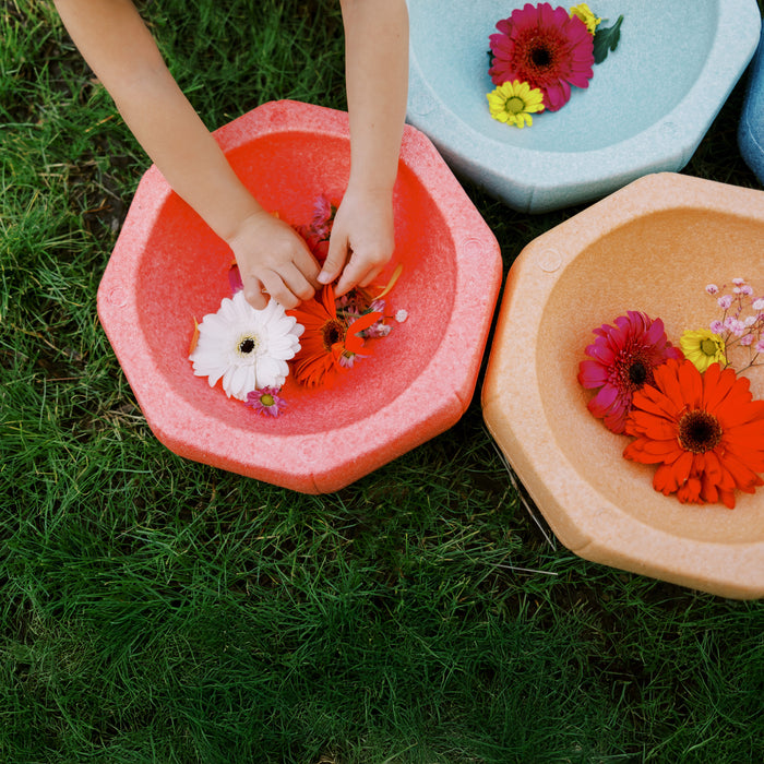 Children arrange flowers in a water-filled orange basin beside blue and beige basins with floating blooms and foam stepping stones on grass. Perfect for indoor or outdoor play with StepPebbles and FREE Balance Board | Pastel set.
