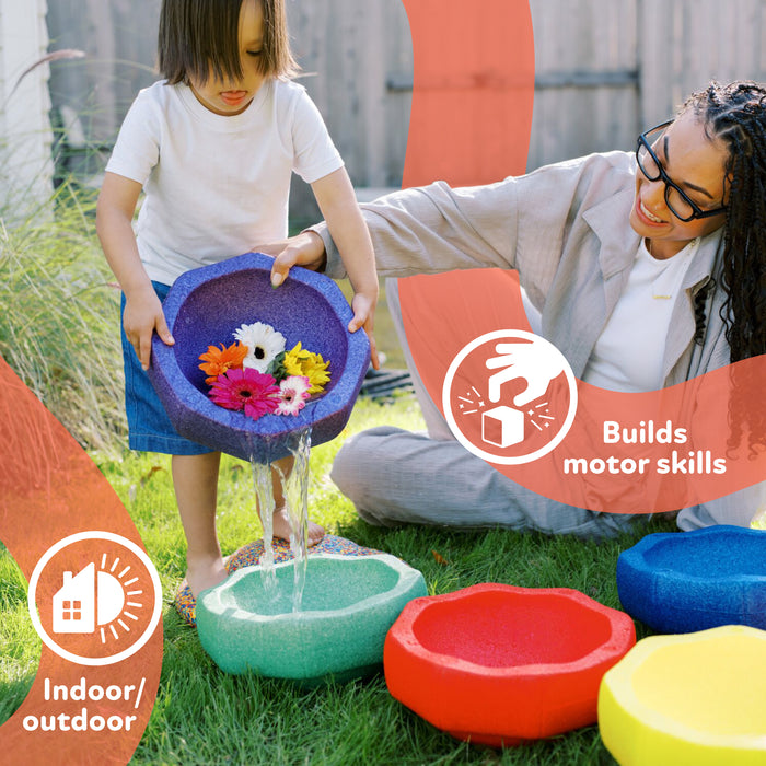 A child pours water and flowers from a colorful bowl while an adult smiles. The StepPebbles and FREE Balance Board | Primary set builds motor skills with eco-friendly play—perfect for indoor or outdoor balance activities.